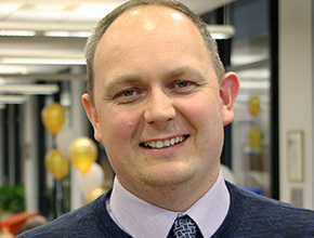 Chris Biggs smiling for a photo at the reception desk